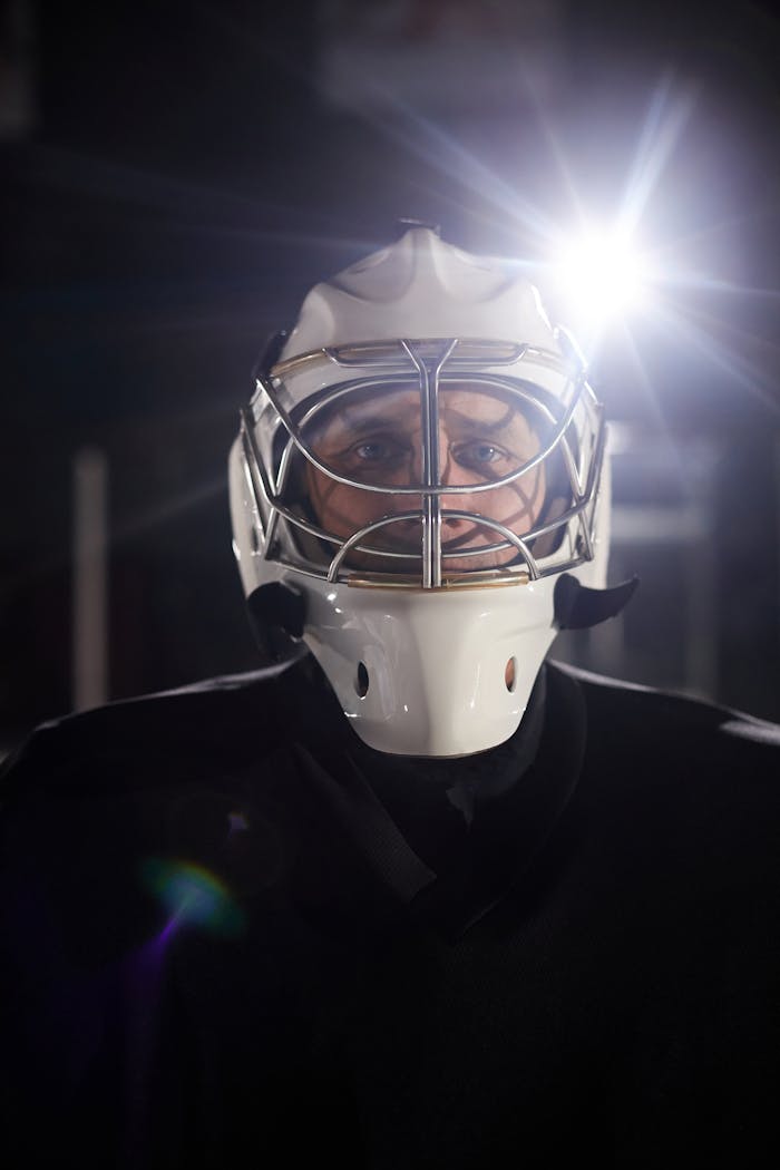 about-01 Portrait of a hockey goalie wearing a mask with a dramatic light flare.