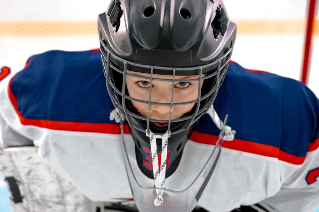 pexels photo 8974646 Close-up of a determined hockey player wearing a helmet and jersey on the ice rink.