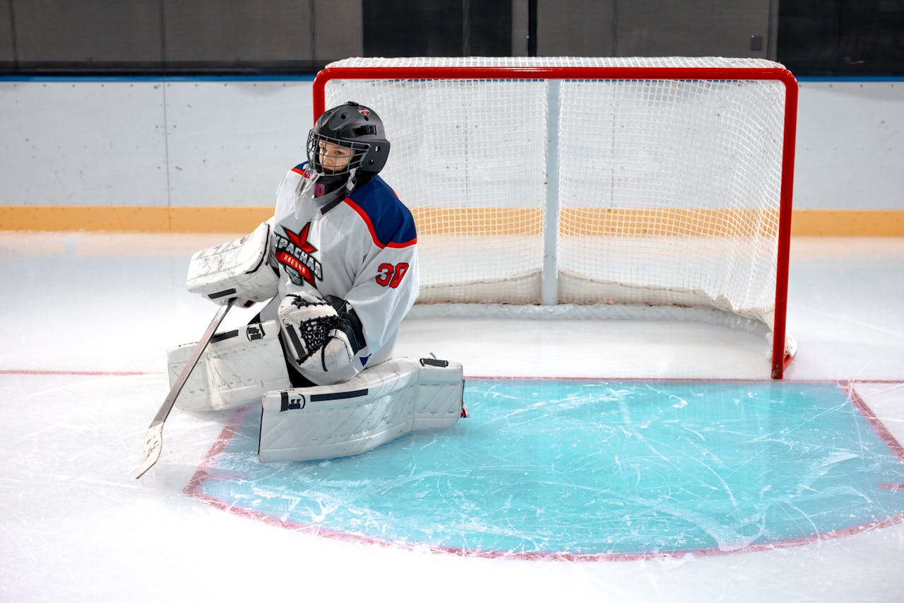 about-03 Ice hockey goalie in full gear kneeling on the ice to defend the goal.